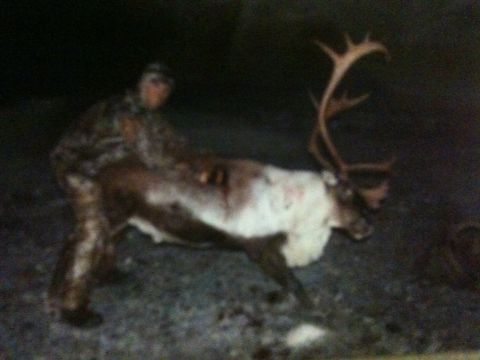 1986 Chevrolet Blazer - A hunter poses with a large reindeer, its impressive antlers clearly visible in the dim light.