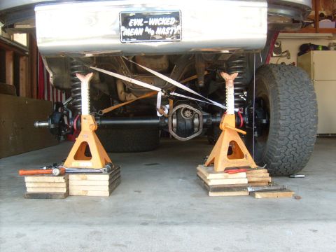 1986 Ford Bronco - The rear axle and suspension of a vehicle are visible, supported by jack stands, with a custom license plate.