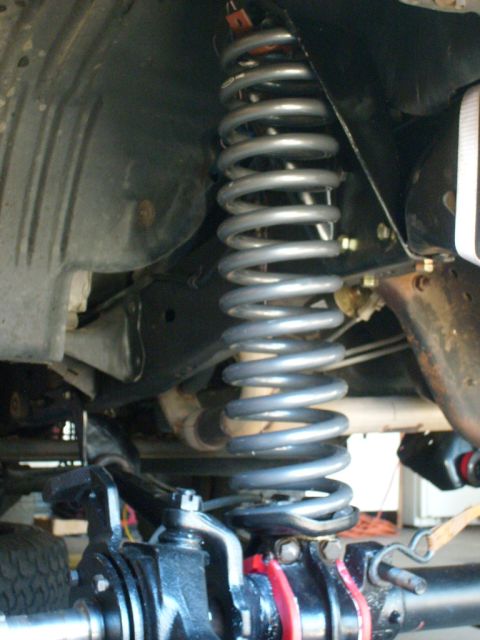1986 Ford Bronco - Close-up view of a vehicle's suspension system, focusing on the coil spring and related components.