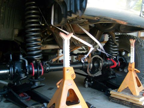 1986 Ford Bronco - Vehicle suspension components are visible, supported by jack stands and straps during maintenance.