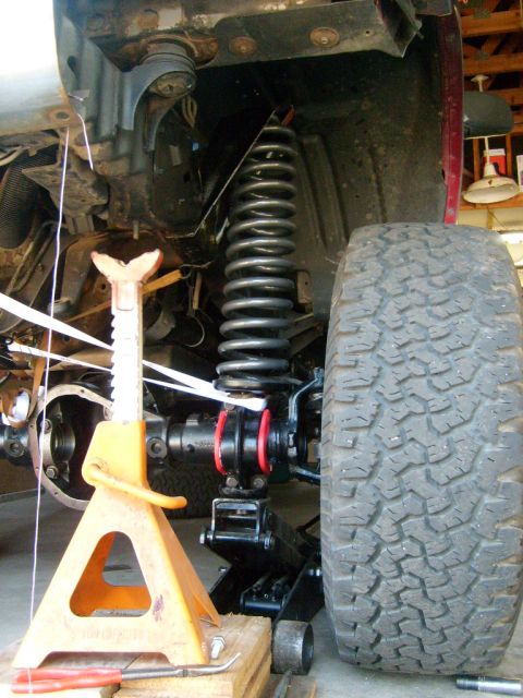 1986 Ford Bronco - Vehicle suspension components and tire are visible, supported by jack stands and a floor jack.