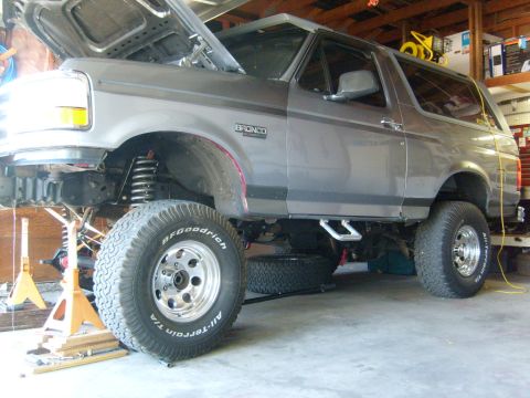 1986 Ford Bronco - This lifted Ford Bronco is undergoing maintenance with its hood up and front end supported by jack stands.