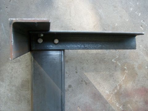1986 Ford Bronco - Close-up view of metal brackets and bolts against a concrete background.