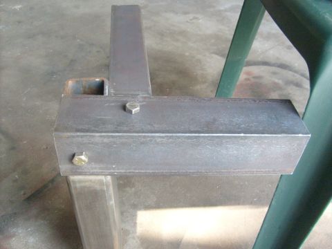 1986 Ford Bronco - A close-up view of a metal frame part, with visible bolts and a portion of a green chair.