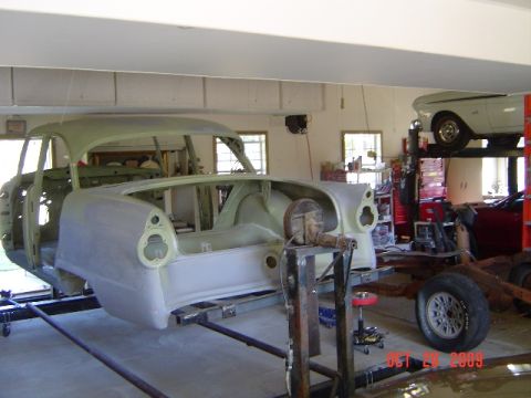 1956 Ford Fairlane - A 1956 Ford Fairlane body is being worked on in a garage, with another vehicle visible on a lift in the background.
