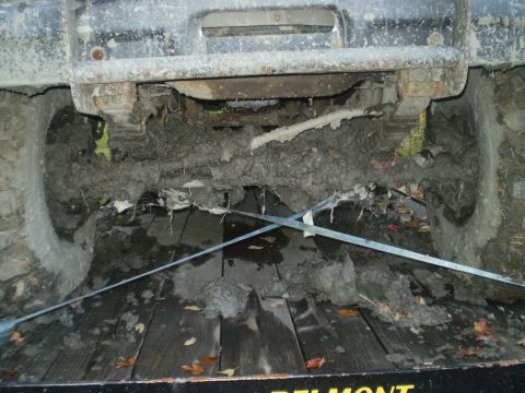 1979 Ford Bronco - The vehicle's undercarriage is heavily caked with mud, indicating recent off-road use.