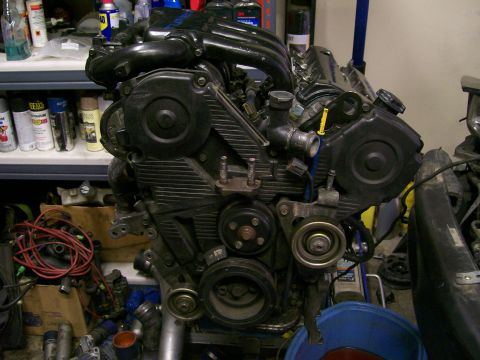 1995 Ford Probe - Engine part shown in a workshop setting with shelves of spray cans in the background.