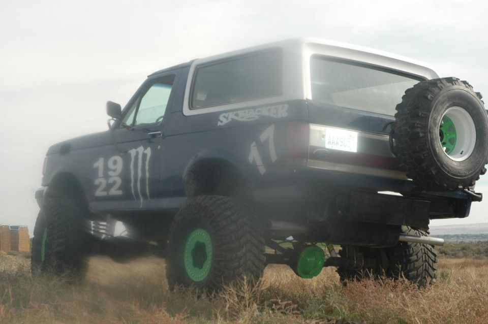 Lifted dark blue SUV with green wheel accents and a rear-mounted spare tire