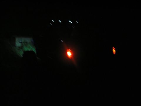 1994 Ford Escort - A blurry nighttime photo shows illuminated vehicle lights against a dark background.