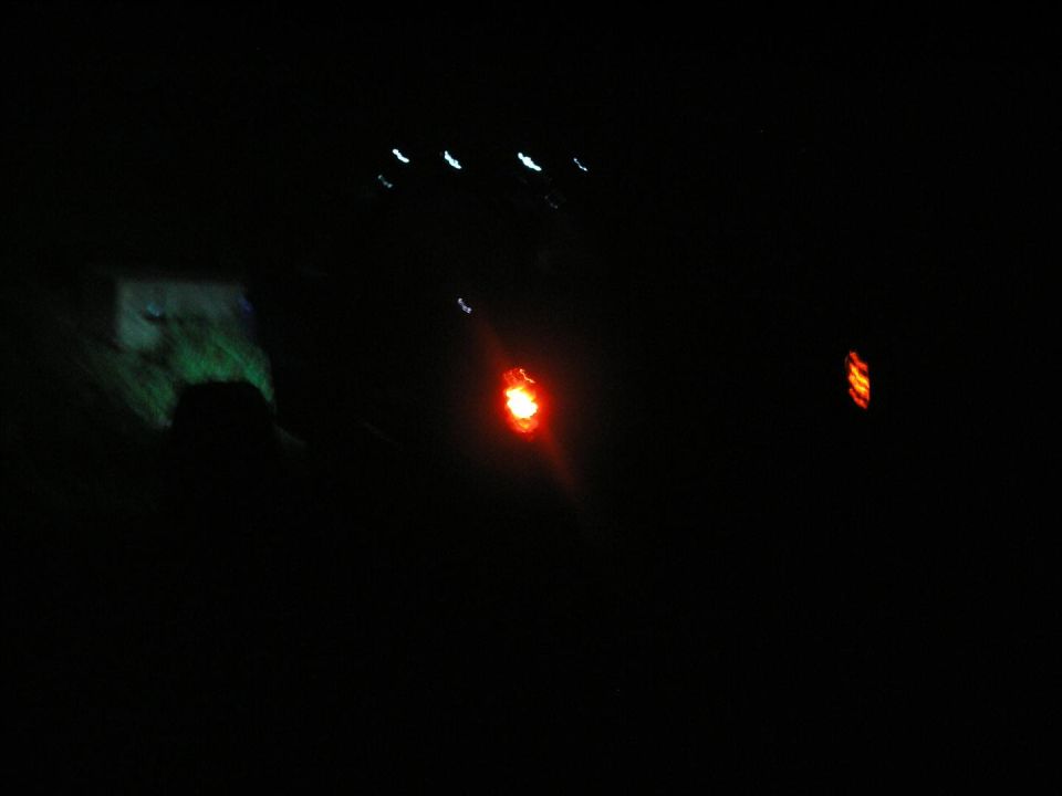Red taillight glowing in the dark, with other lights in the distance