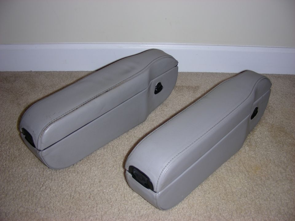 Two gray car armrests sitting on a carpeted floor