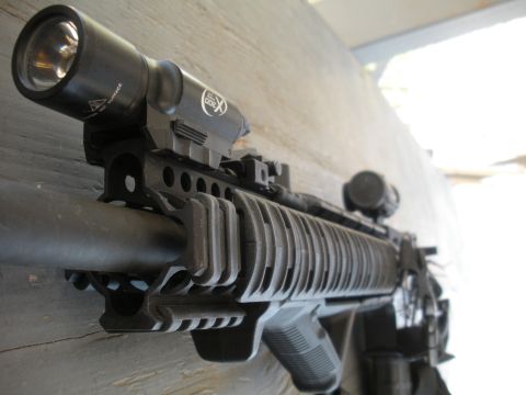 1996 Ford Bronco - Close-up view of an assault rifle's handguard, a mounted tactical flashlight and scope.