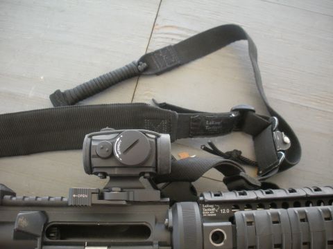 1996 Ford Bronco - Close-up of a rifle's tactical accessories, including a sling and optic, resting on a wooden surface.