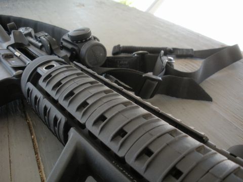 1996 Ford Bronco - An assault rifle with a tactical scope is shown in detail, positioned on a weathered wooden surface.