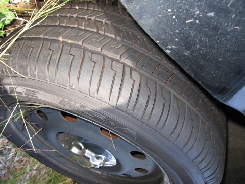 1991 Ford LTD Crown Victoria - A close-up view of a car's tire and fender, with grass visible in the background.