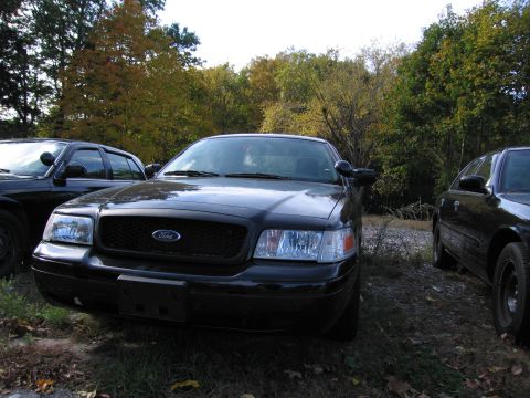 1991 Ford LTD Crown Victoria - Front view of a black Ford Crown Victoria, parked outdoors with other similar vehicles.
