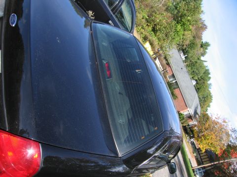1991 Ford LTD Crown Victoria - Rear view of a black sedan parked outdoors with trees and a house in the background.