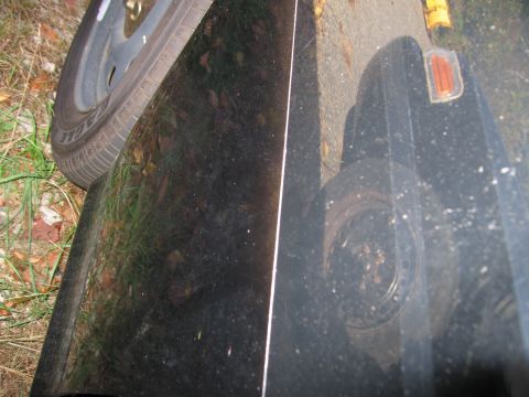 1991 Ford LTD Crown Victoria - Close-up of a black car's fender and tires, with an orange marker light visible.