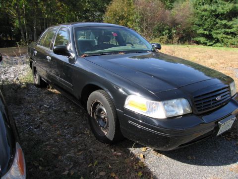 1991 Ford LTD Crown Victoria - This black Ford Crown Victoria is parked on a gravel surface with dry leaves scattered around.
