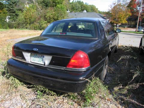 1991 Ford LTD Crown Victoria - This black Ford Crown Victoria is parked on a gravel lot with overgrown grass.