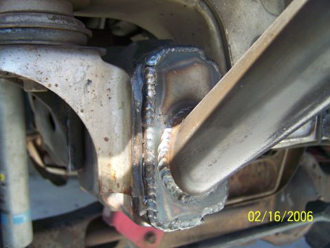 1995 Ford Bronco - Close-up view of a heavily modified suspension component with visible welds and signs of wear.