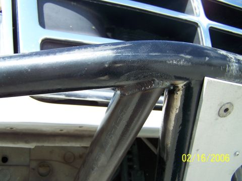 1995 Ford Bronco - Close-up of a black roll cage mounted in front of the chrome grille of a 1995 Ford Bronco.