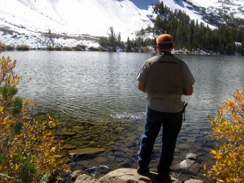 1996 Ford Bronco - Man fishing by a lake in a mountainous area with snow on the peaks.