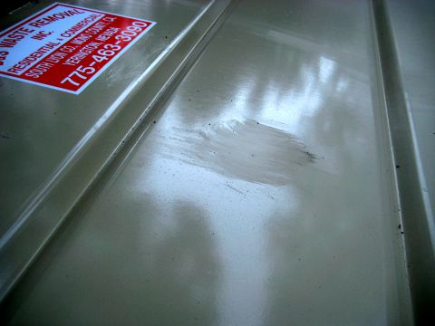 1996 Ford Bronco - Sticker on a beige surface, possibly a vehicle or container, for waste removal services.