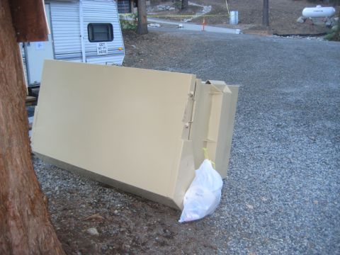 1996 Ford Bronco - A large beige metal container sits on a gravel surface next to a trailer. A bag of trash is visible.