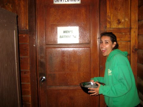 1996 Ford Bronco - A woman stands in front of a wooden door with a sign for the men's bathroom.
