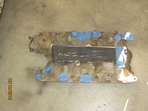 1994 Ford Bronco - A dirty engine intake manifold is taped up and lies on a concrete floor.