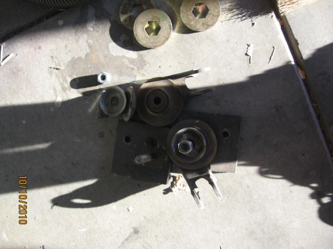 1994 Ford Bronco - Various metal components and fasteners are scattered on a concrete surface, casting long shadows.