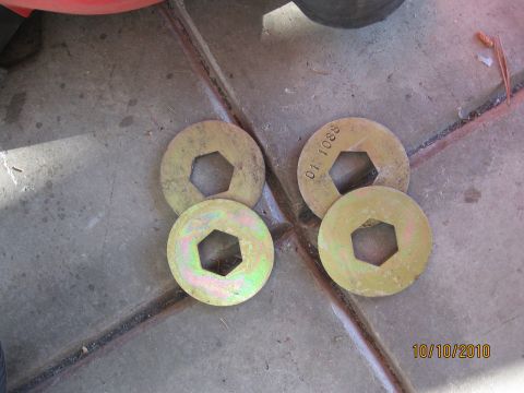 1994 Ford Bronco - Four metal washers with hexagonal holes are visible on a concrete surface, with one washer showing stamped text.
