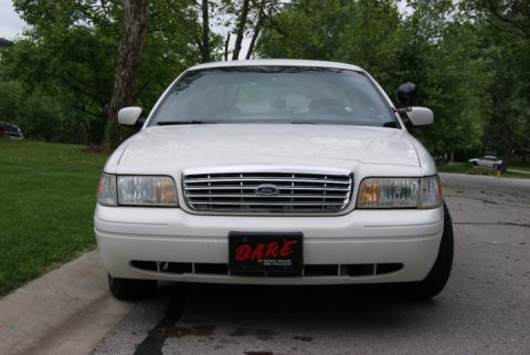 1999 Ford Crown Victoria - Front view of a white 1999 Ford Crown Victoria, parked outdoors with trees and grass visible.