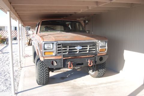 1982 Ford Bronco - Front view of a brown Ford Bronco with off-road modifications parked in a covered area.