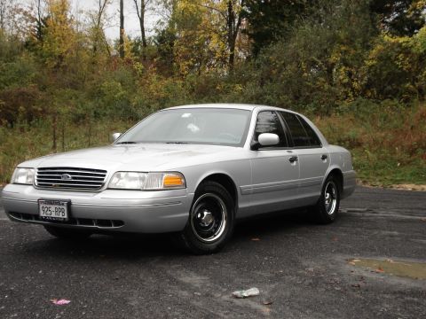 2000 Ford Crown Victoria - Silver 2000 Ford Crown Victoria parked on asphalt with autumn foliage behind it.