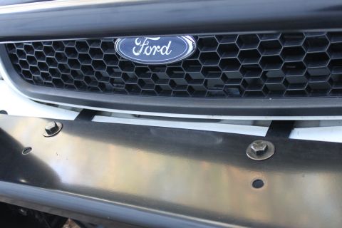 2003 Ford Crown Victoria - Close-up of a Ford grille and a push bar, indicating a vehicle front.