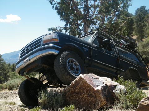 1982 Ford Bronco - This Ford Bronco is navigating a rocky trail with its front tire on a large boulder.