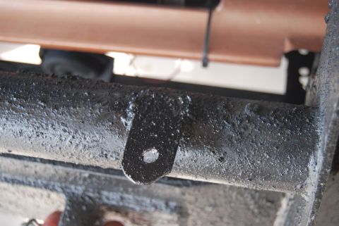 1982 Ford Bronco - Metal bracket attached to a greasy pipe, likely part of a vehicle's frame or suspension.