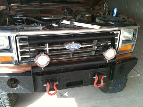 1982 Ford Bronco - Front view of a Ford Bronco with an aftermarket bumper and auxiliary lights. Hood is open.