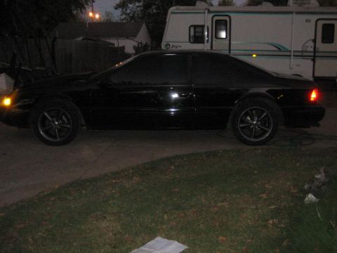 1996 Ford Thunderbird - Side profile of a black 1996 Ford Thunderbird coupe with aftermarket wheels.