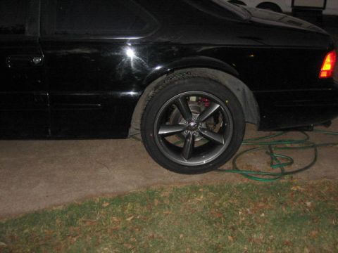 1996 Ford Thunderbird - The rear quarter panel and wheel of a black 1996 Ford Thunderbird are visible in this side view.