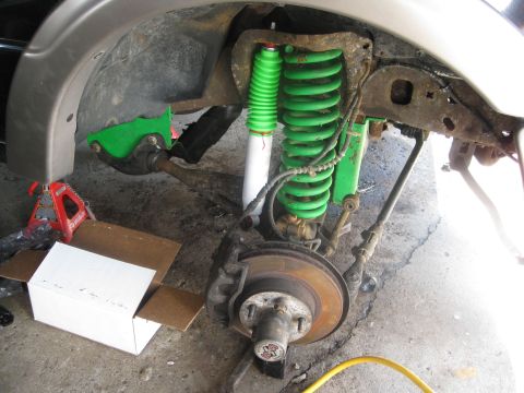 1995 Ford Ranger - The front suspension and brake assembly of a vehicle is shown, with aftermarket green springs and white shocks installed.