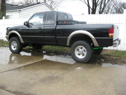 1995 Ford Ranger - This black 1995 Ford Ranger pickup truck is shown from the side, parked in a wet, reflective area.