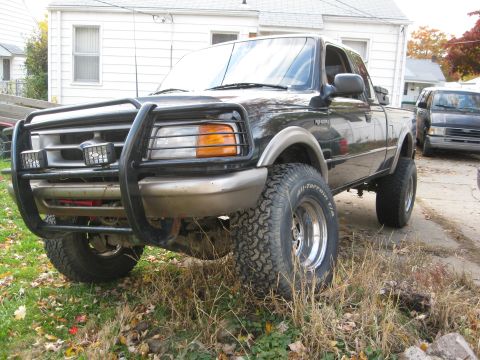 1995 Ford Ranger - A lifted black Ford Ranger pickup truck is parked in a driveway with a brush guard and off-road tires.