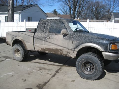 1995 Ford Ranger - This 1995 Ford Ranger pickup truck is heavily covered in mud, obscuring much of its original paint and details.