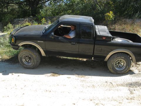 1995 Ford Ranger - Black 1995 Ford Ranger pickup truck with a driver and off-road tires is seen from the side.