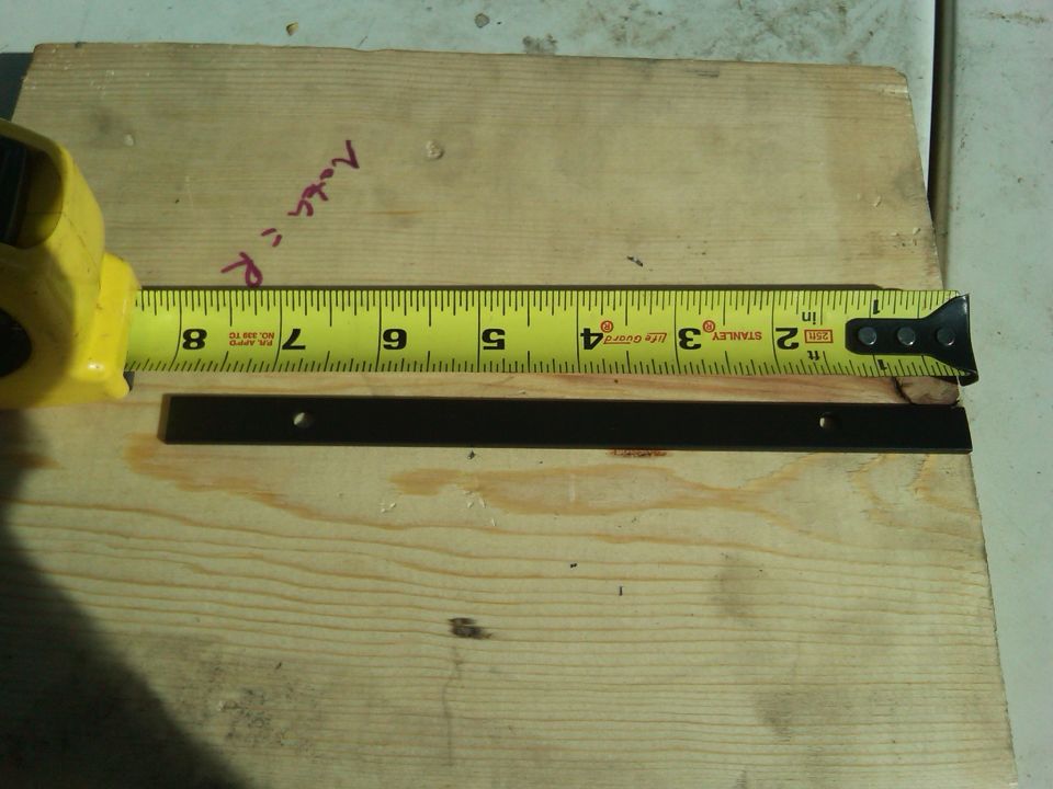 Stanley tape measure measuring a metal bracket on a plywood surface