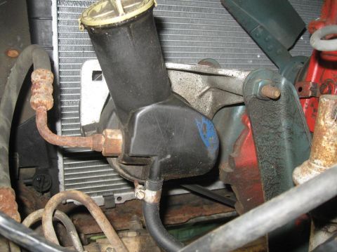 1981 Ford Bronco - Close-up view of the power steering fluid reservoir and fan shroud, with visible rust on hoses.