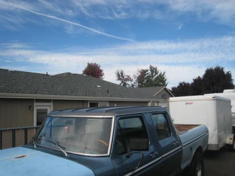 1976 Ford F-250 - A blue 1976 Ford F-250 pickup truck is seen from a 3q-front angle, towing a white trailer under a partly cloudy sky.